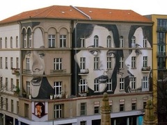 Вуличний художник малює обличчя жінок на стінах будинків